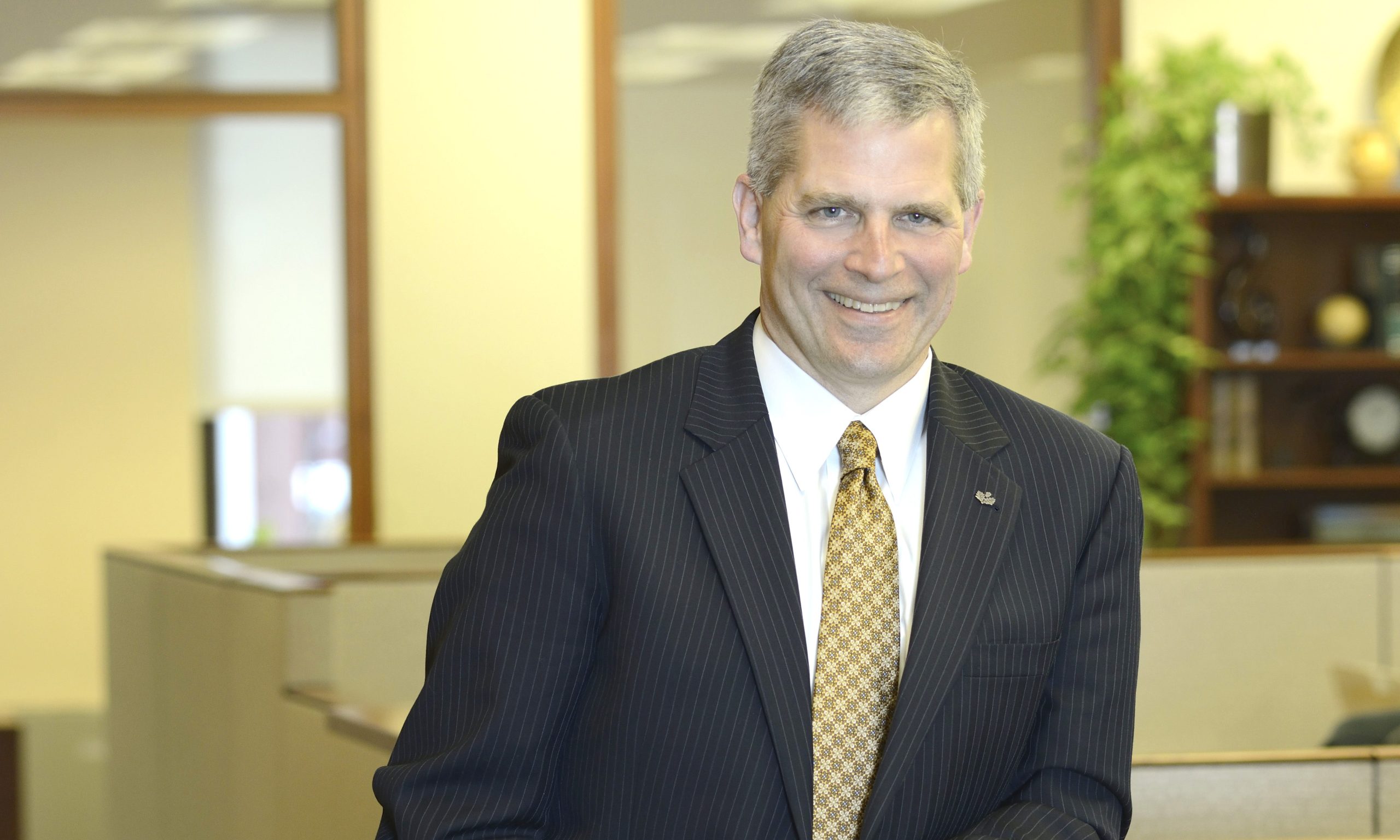 Greg Hartz, CEO of Tompkins Bank, stands in an office environment.