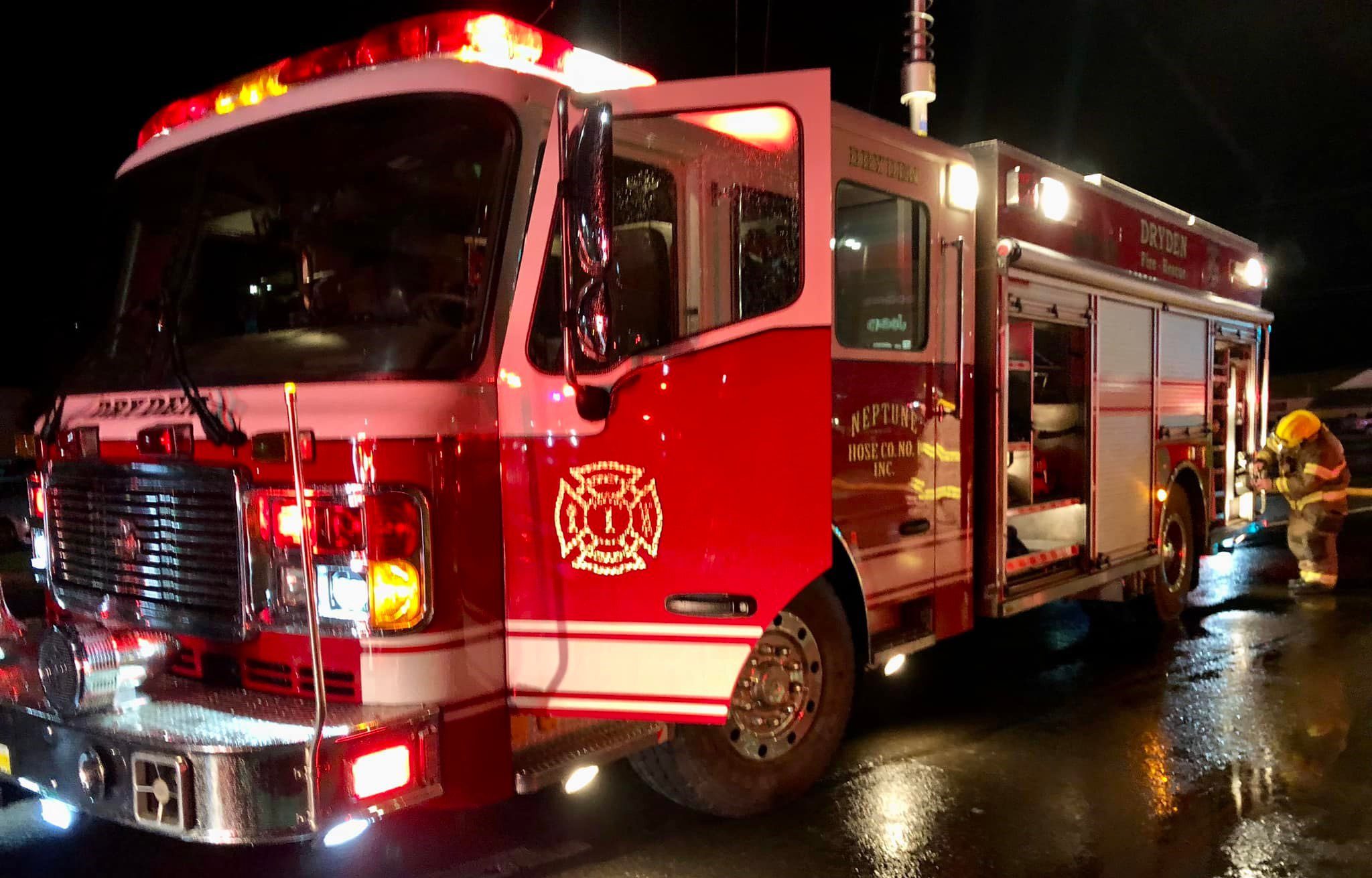 A bright red Dryden firetruck in the evening, lights on