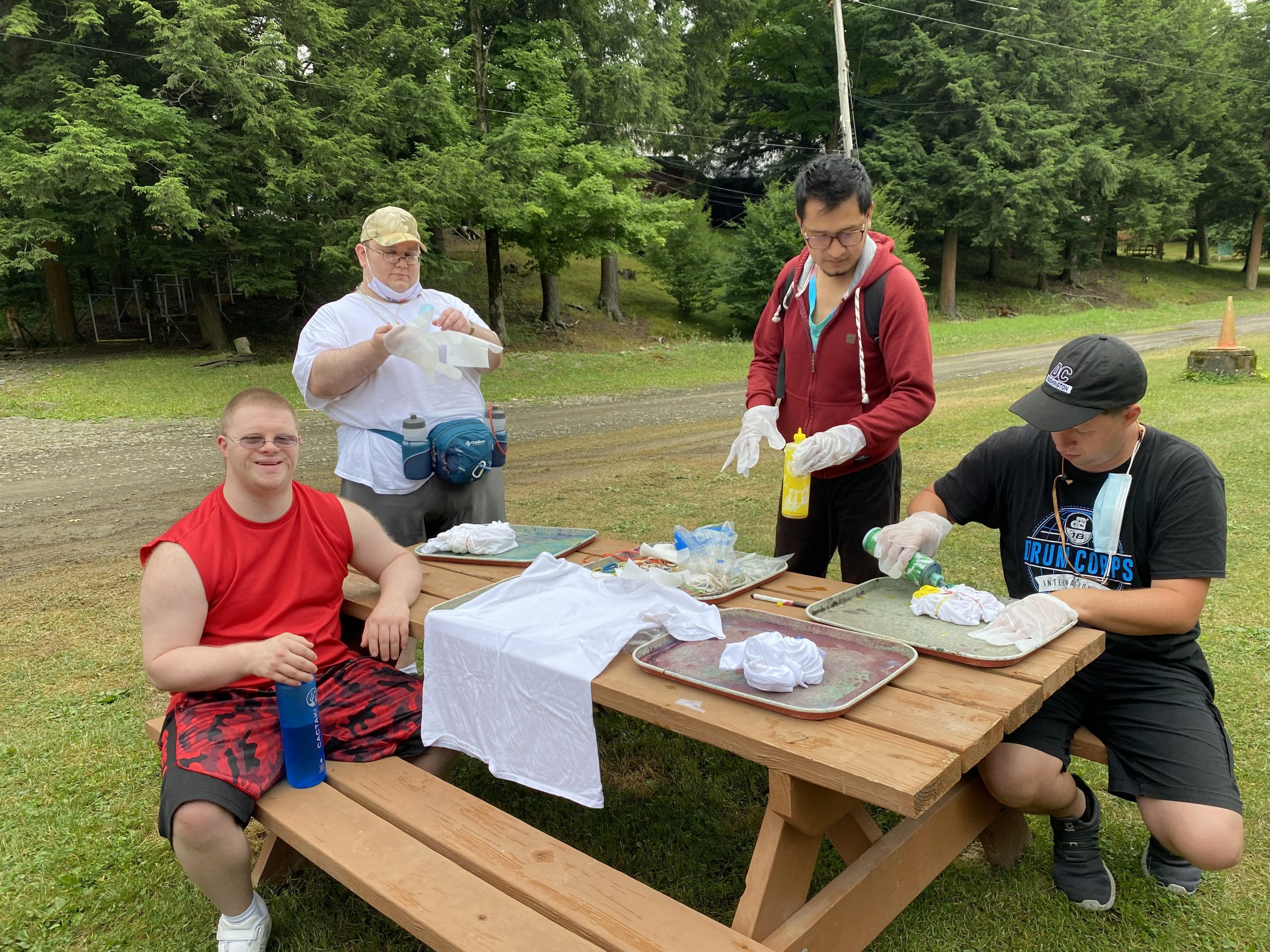 four people sitting around a picnic table tie-dying shirts