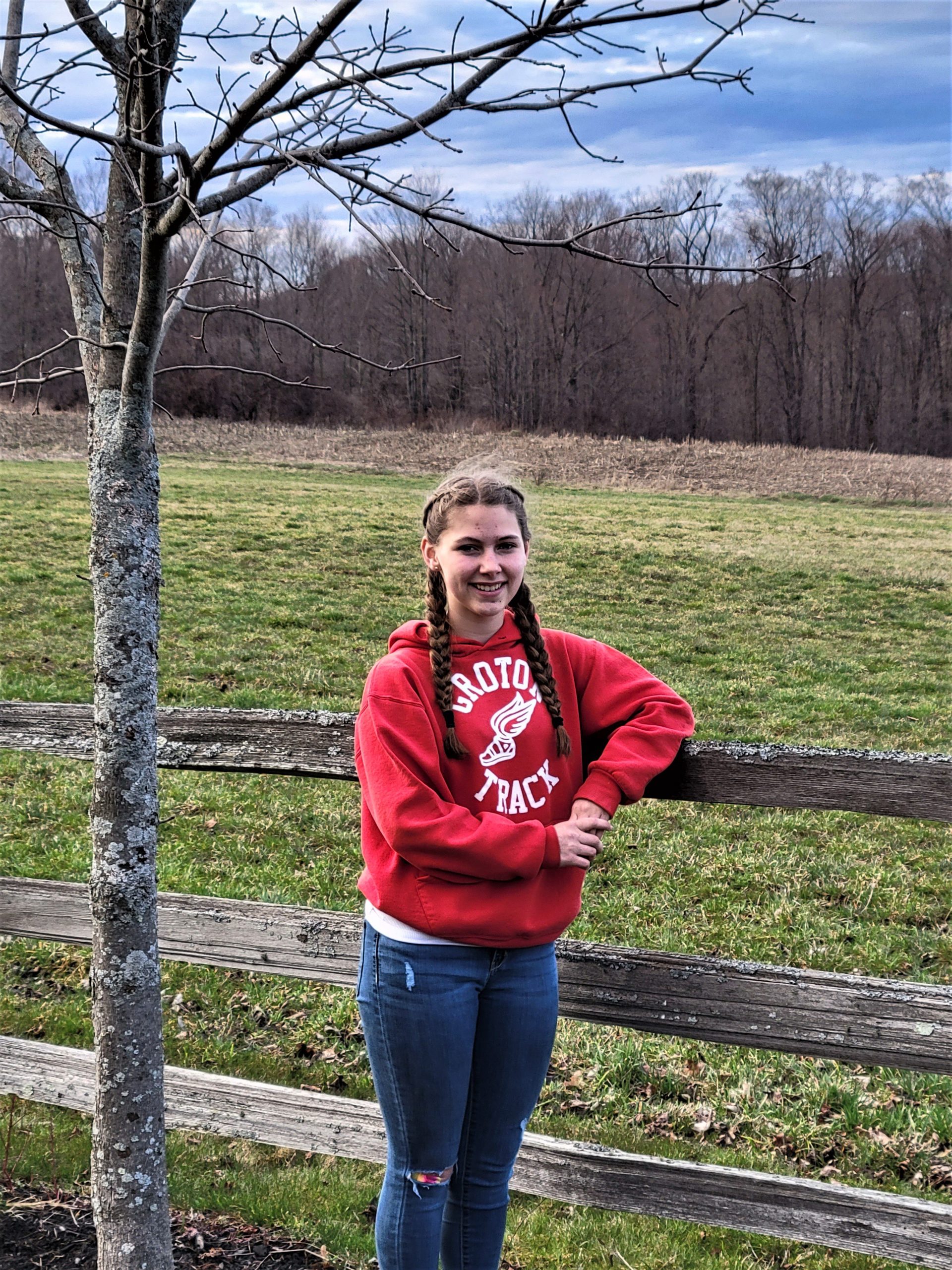 Addie Clore leans on a fence in front of an open field
