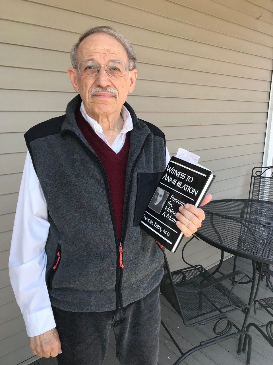 Severin holds his father's book on the porch of his home in Tompkins County.