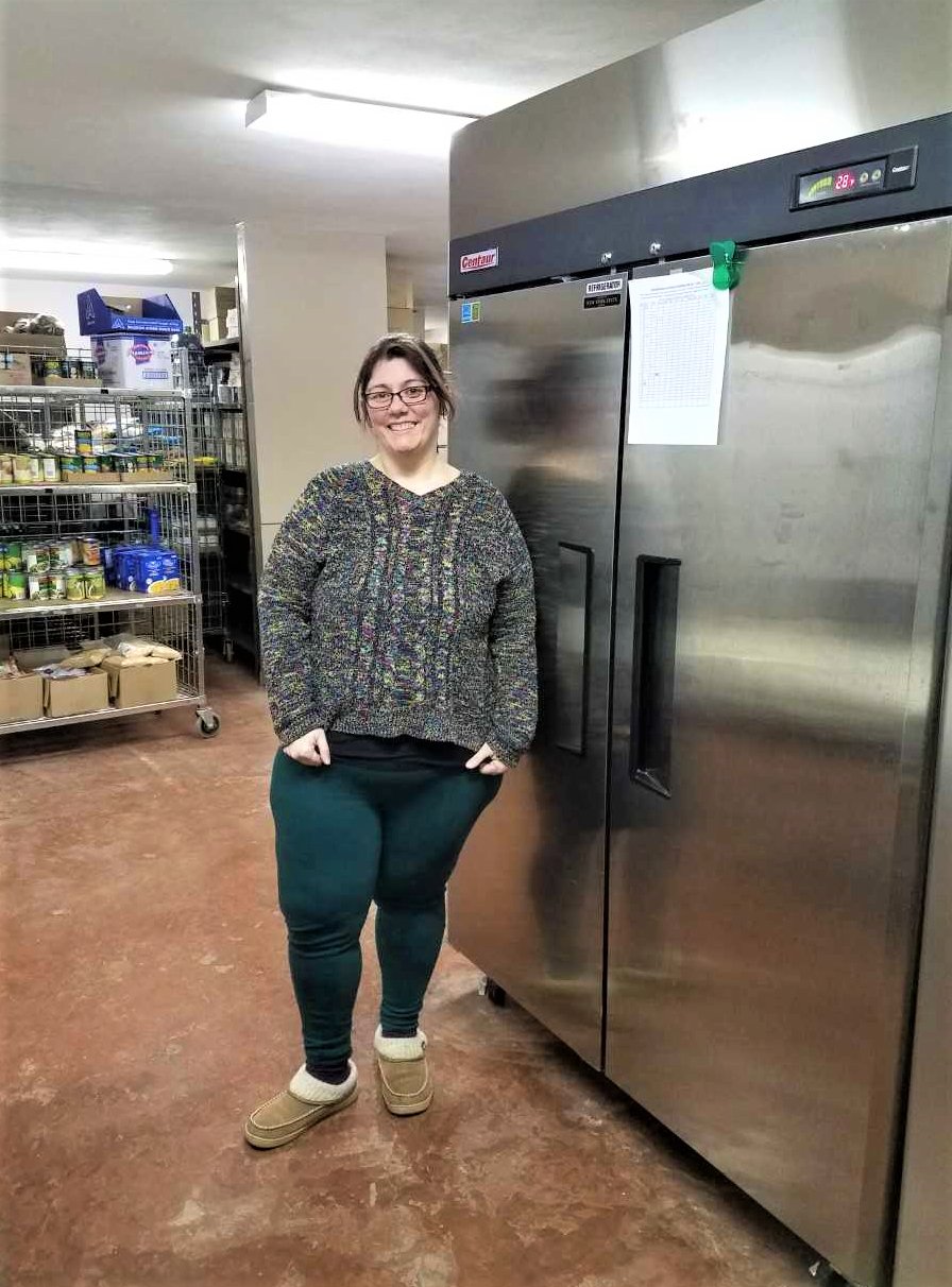 Groton Food Pantry coordinator, Jess Stone, standing by one of the double-door refrigerators in the GFP, as she excitedly anticipates the arrival of another one just like it from the Food Bank of the Southern Tier.