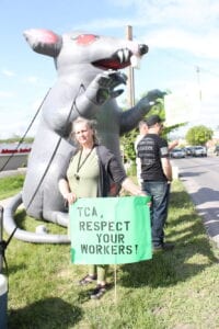 Ruth Williams poses with her sign at the Friday, May 24 action event not far from the TCA offices off of Route 13.