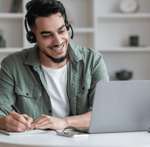 a man looking at his laptop while taking notes