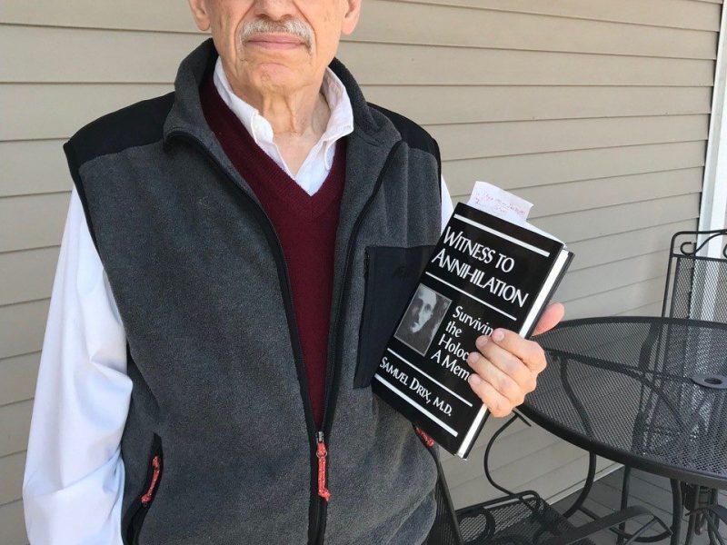 Severin holds his father's book on the porch of his home in Tompkins County.