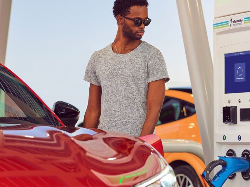 a man stands at a charging station with his electric vehicle