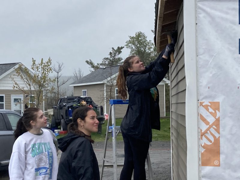 Amelia Baumann, Abigail Marra-MacGregor and Madison Bell from Ithaca College Habitat for Humanity help with the woodshed being built at Second Wind Cottages.