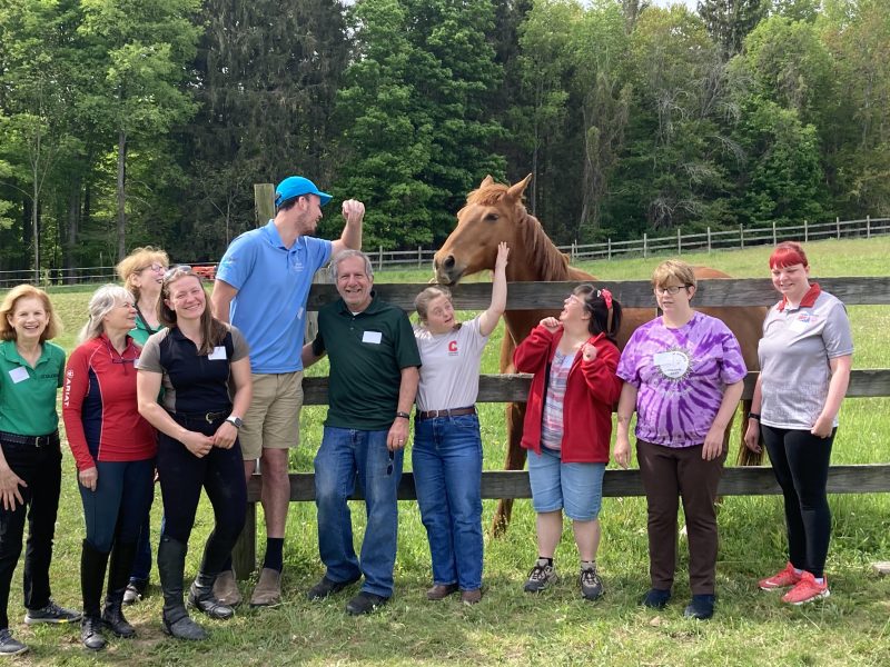 Susan Schwartz, Paula J. Wedemeyer, Lisa Krizman, Hannah Roman, Andrew Hay, Bob Krizman, Emma Dodici, Amy Cusano, Jessica Tunison and Kinsley Henry pose with Buddy at Stablework in Newfield. Stablework will host the Tompkins Cortland Special Olympics equestrian training beginning in June.