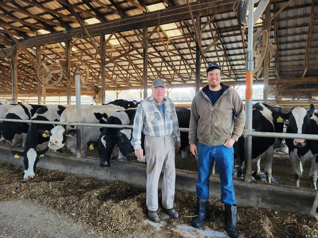 Photo by Linda Competillo 
Dan Carey (left) and his son, Eric, are pictured here standing in one of their dairy barns. The Carey Farm in Groton is designated a New York State Dairy of Distinction. Weather has made things a bit challenging for the Careys and others in the area this year.
