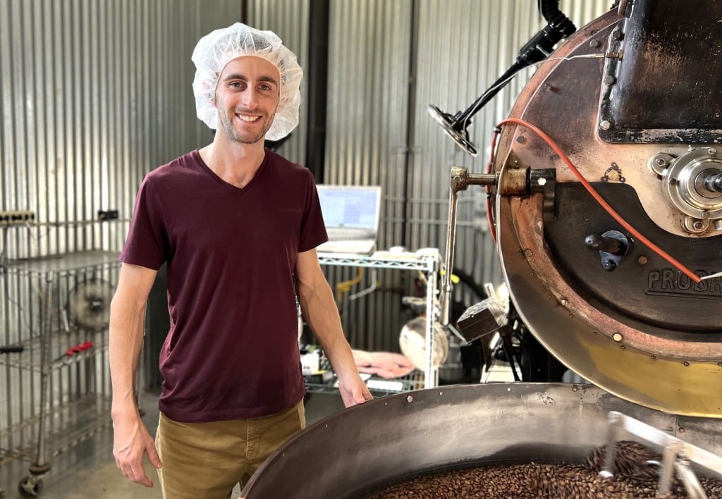 By Jaime Cone Hughes 
Matthew Thompson, roaster and production assistant at Gimme! Coffee, with the company’s 1945 coffee roaster. Gimme! roasts coffee at its Krums Corners roastery four days a week, taking Fridays off to complete regular maintenance on the 80-year-old machine. 