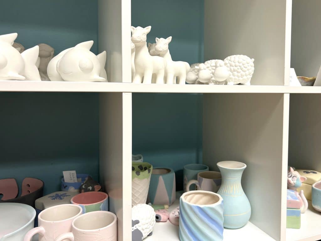 Photo by Jaime Cone Hughes 
Clay animals, mugs and other items, some unpainted and some painted by the members of a recent class, line the shelves of Claybird Pottery Studio. 